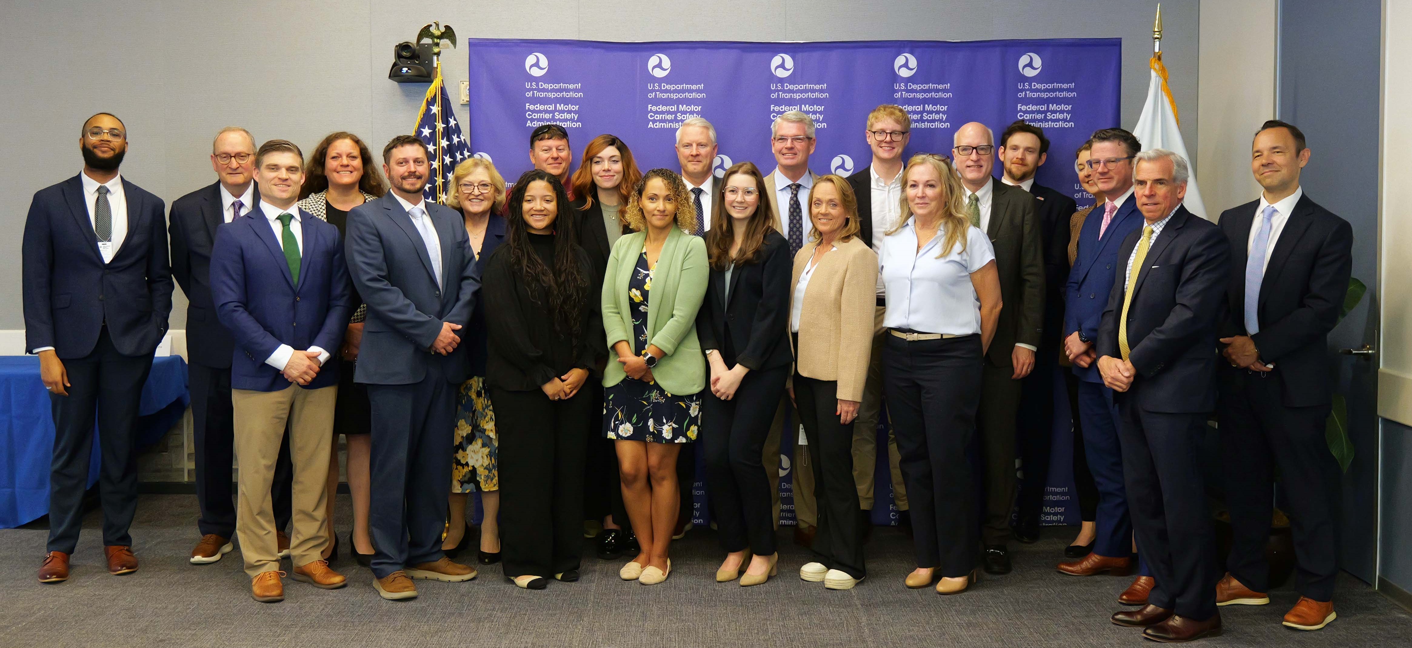 Group of people standing together in front of a step and repeat that has FMCSA logos
