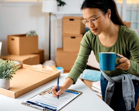 a woman using the protect your move checklist with moving boxes in the background